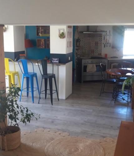 uma sala de estar com cadeiras e uma mesa e uma cozinha em Chambre d hôtes em Saint-Symphorien-dʼAncelles
