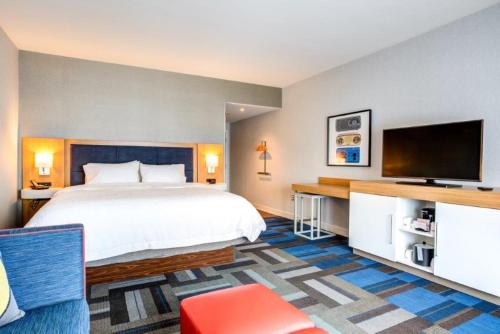 a hotel room with a bed and a flat screen tv at Hampton Inn & Suites Boston/Waltham in Waltham