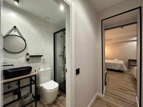 a bathroom with a toilet and a sink and a mirror at CC Opera Suites in Madrid
