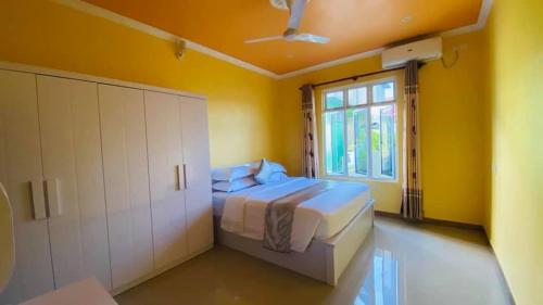 a yellow bedroom with a bed and a window at Maavaharu - K.Huraa in Huraa