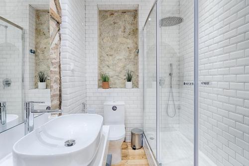 a white bathroom with a sink and a shower at Architectural Gem in Bica in Lisbon