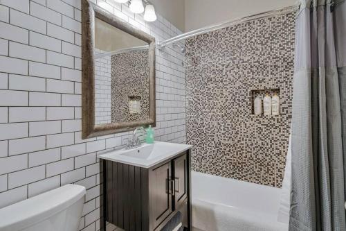y baño con lavabo, bañera y espejo. en The Village Inn by Dakota Gal Digs en Chicago