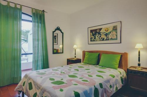 a bedroom with a bed with green curtains and a window at Vila Mourisca in Armação de Pêra
