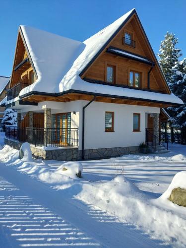 a house with a snow covered roof at Pokoje Gościnne ZYCH - Domek in Chochołów