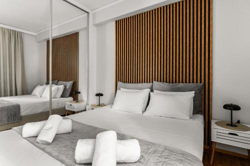 a white bedroom with two beds and a mirror at Sunset Escape & Spa in Athens