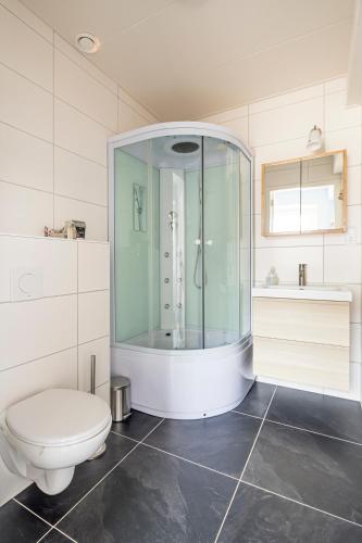 a white bathroom with a toilet and a shower at Het Kamphuis, landelijk slapen in Heerhugowaard