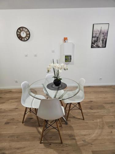 une table en verre avec des chaises blanches et un vase avec des fleurs dans l'établissement T2 chaleureux, calme et entièrement rénové., à Béziers