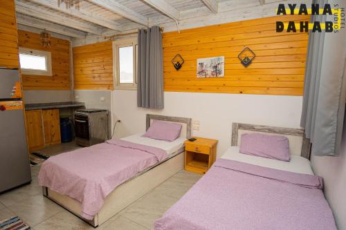 Ayana Hotel Dahab في دهب: سريرين في غرفة بجدران خشبية