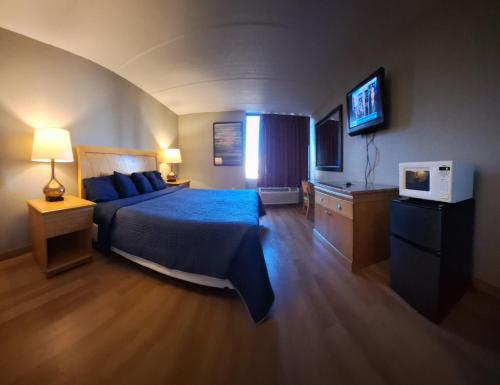 una camera con letto blu e televisore di Madison Inn & Suites a Madison
