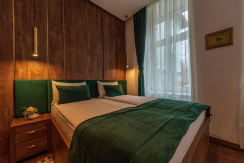 a bedroom with a bed with a green comforter and a window at Studio Apartmani 071 Free Garage Parking in Sarajevo