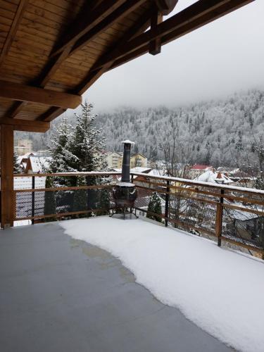 a snow covered porch with a stove on a fence at Casa Zaharia Azuga in Azuga