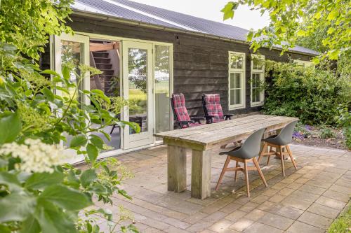 un patio con tavolo e sedie in legno di Het Kamphuis, landelijk slapen a Heerhugowaard
