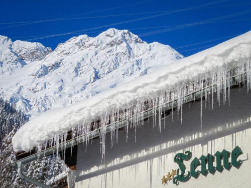 a snow covered roof with icicles on it with a snow covered mountain at Hotel Tenne in Sankt Anton am Arlberg