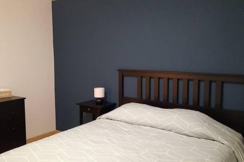 een slaapkamer met een bed en een blauwe muur bij Le Cocon des Prés in Saint-Hubert