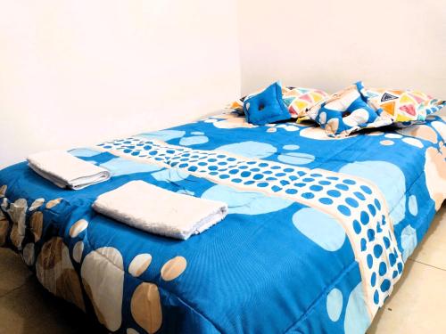 Una cama con un edredón azul con toallas. en Tu hogar lejos de casa., en Garzón