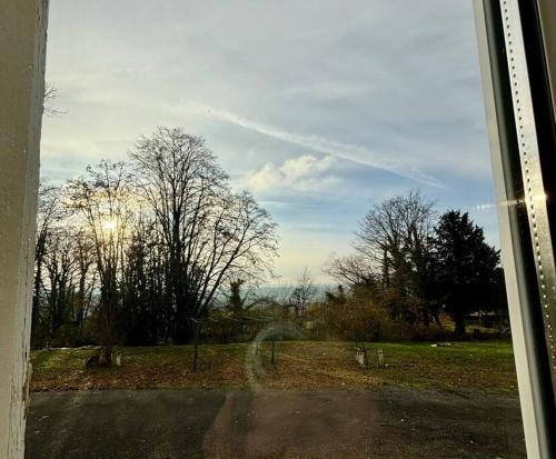 a view from a window of a field with trees at « Aux Marronniers » 