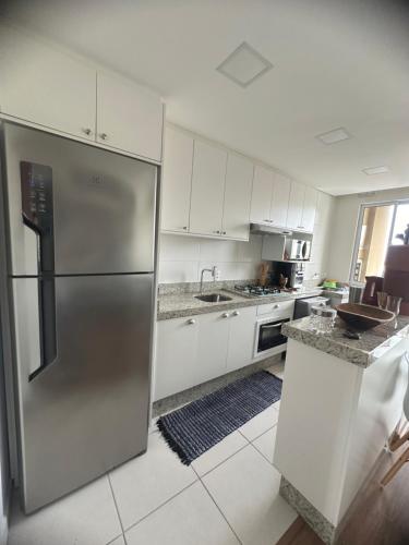 a kitchen with a stainless steel refrigerator and white cabinets at Resort Apto Frente Mar in Barra Velha