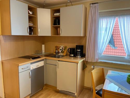 a small kitchen with white cabinets and a window at Haus Delphin - Ferienwohnung 1 in Norderney