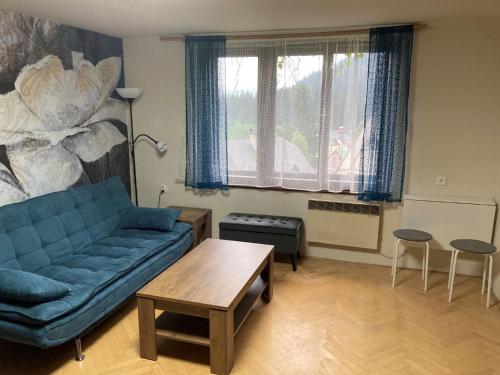 Apartmán Rekys في Jiřetín pod Bukovou: غرفة معيشة مع أريكة زرقاء وطاولة