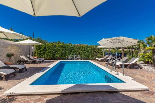 a swimming pool with chairs and umbrellas next to at Guest House Antonella in Malinska