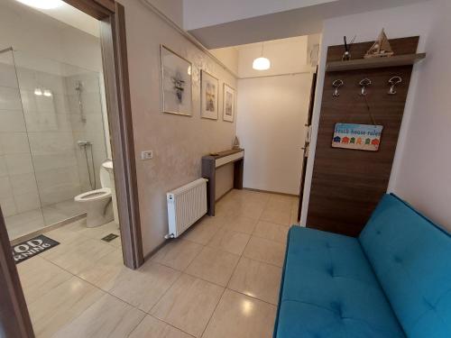 uma casa de banho com um chuveiro, um WC e um sofá azul em BlueSea Summerland Apartments em Mamaia