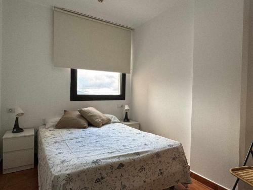 a white bedroom with a bed and a window at Apartamento Girasol in Sierra Nevada