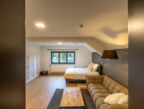 ein Wohnzimmer mit einem Sofa und einem Bett in der Unterkunft Villas Seven - Les chambres in Jalhay