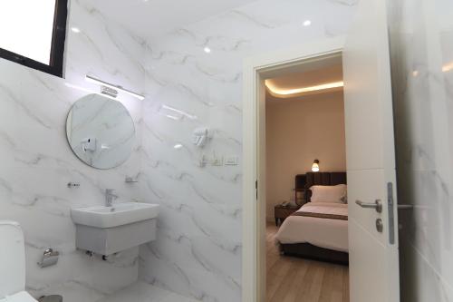 a bathroom with a sink and a mirror and a bed at Zemilo Hotel Apartment in Addis Ababa