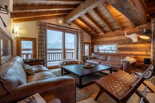 a living room with leather couches and a table at Chalet Chardon Bleu in Méribel