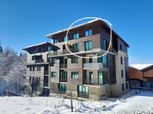 un edificio de apartamentos con nieve en el suelo en Duplex apartment near the forest en Bakuriani