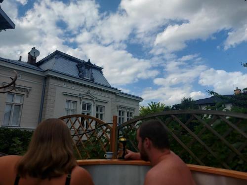 a man and a woman sitting on a balcony in front of a house at Apartmán U Borovice in Rychnov nad Kněžnou
