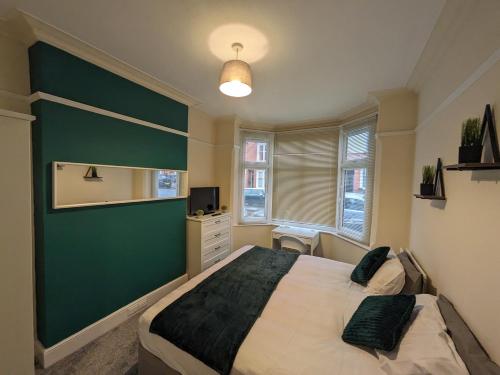 a bedroom with a large bed and a green wall at Beacon House in Leicester