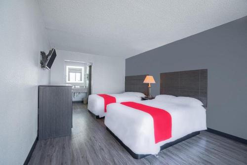 um quarto de hotel com duas camas com toques vermelhos em StateLine Stayovers Extended Stay Hotel em Texarkana