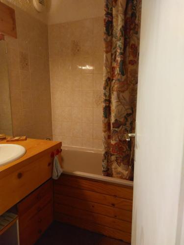 a bathroom with a tub and a sink and a shower curtain at Résidence Les Eterlous - Joli Studio Cabine 2 Adultes et 2 Enfants Wifi in Val Thorens