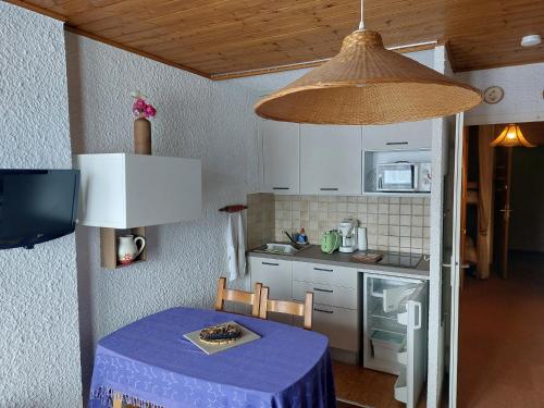 una pequeña cocina con mesa y mantel púrpura en Val Thorens Studio Cabine 4 Personnes en Val Thorens