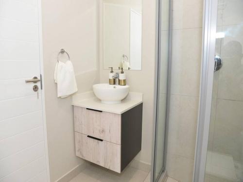 een witte badkamer met een wastafel en een douche bij Elcaro Luxury Villas-Urban Taupe in Midrand