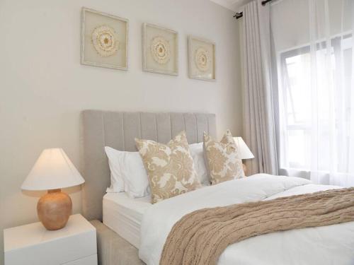 een witte slaapkamer met een bed en een raam bij Elcaro Luxury Villas-Urban Taupe in Midrand