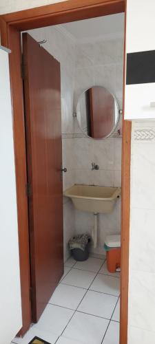 La salle de bains est pourvue d'un lavabo et d'un miroir. dans l'établissement Kit Nana, à Praia Grande