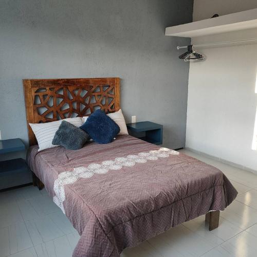 a bed with two blue pillows on it in a room at Bonito departamento in Morelia
