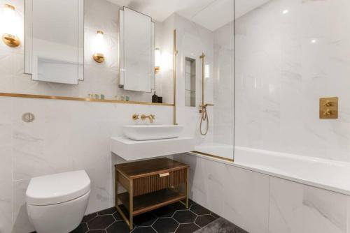 Baño blanco con aseo y lavamanos en Chic Chelsea 1BR Luxe Retreat, Serene Balcony en Londres