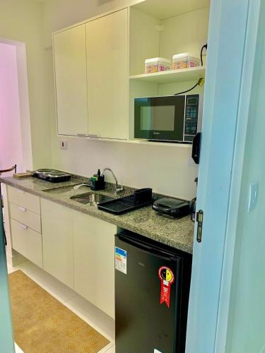 a kitchen with a black refrigerator and a microwave at Studio Vertentes in Sao Paulo