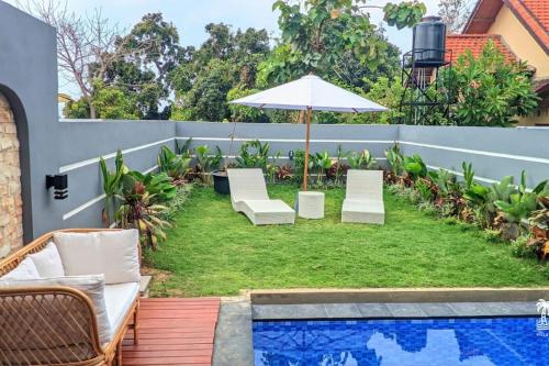 un patio con sillas y una sombrilla junto a la piscina en Villa HBNR Two-Bedroom Tiny House with Private Pool in Bali, en Babakan Sangsit