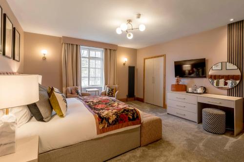 a bedroom with a bed and a desk and a television at Borrowdale Gates Hotel in Keswick