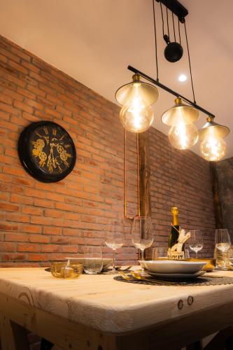 - une table avec des verres à vin et une horloge sur un mur de briques dans l'établissement Édouard & Richard, à Colmar