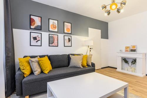 uma sala de estar com um sofá cinzento com almofadas amarelas em Travelers Hideout - Central Apartment em Brasov