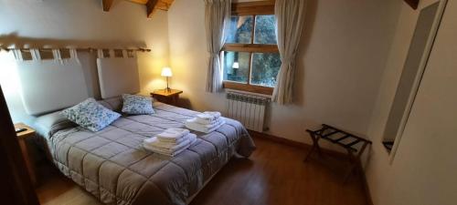 1 dormitorio con cama y ventana en Apart Hotel Bungalows El Viejo Cipres en San Carlos de Bariloche