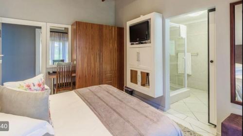 um quarto com uma cama e uma televisão num quarto em Richtershuyz Luxury Accommodation em Pretoria