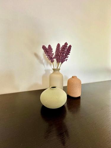 a white vase with purple flowers in it on a table at L'annexe du domaine de brisset in Montélimar