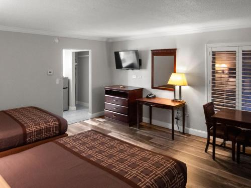 a hotel room with a bedroom with a desk and a bed at Dream Inn in Fresno