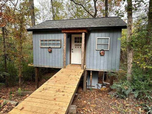 una casa azul con una pasarela de madera en el bosque en Treehouse at Berry-patch en Longview